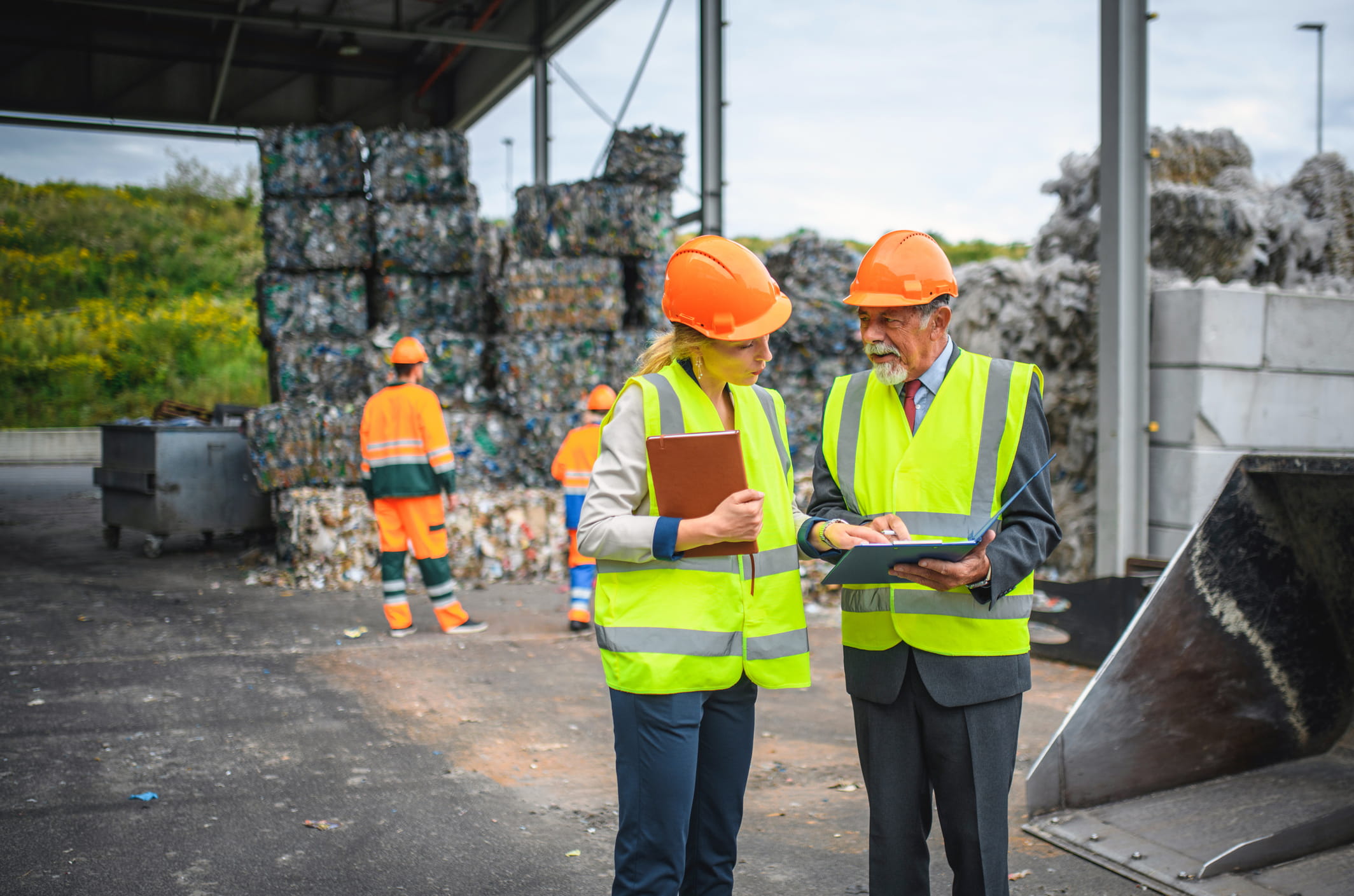 man and woman holding clipboard at job site reviewing document